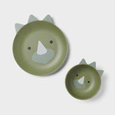 two green plates with faces on them, one is shaped like a cat and the other has an animal face