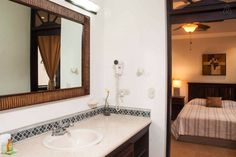 a bathroom sink sitting under a mirror next to a bed in a room with white walls