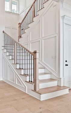 a white staircase with wooden handrails and wood flooring in an empty room