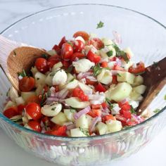 a glass bowl filled with chopped vegetables and a wooden spoon on top of the bowl