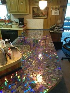 a kitchen counter covered in lots of colorful glass tiles on it's sides and back