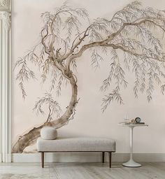 a white bench in front of a wall with a tree painted on it and a table next to it