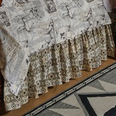 a bed with a white and black bedspread on top of it next to a rug