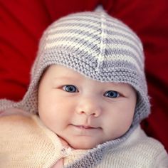 a baby is wearing a knitted hat and looking at the camera with blue eyes