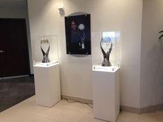 three white pedestals with vases on them in a room