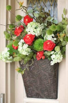 a vase filled with red and white flowers sitting on top of a door sill