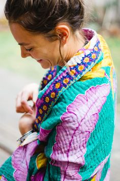 a woman in a colorful jacket looking at her cell phone