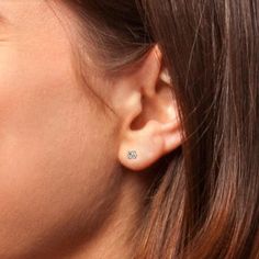 a close up of a person's ear wearing a pair of earrings with diamonds