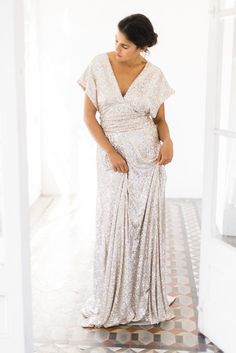 a woman in a white dress standing on a tiled floor with her hands behind her back