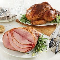 two plates with ham on them and silverware next to each other in front of the turkey