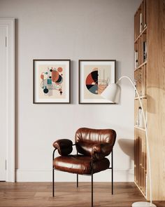 two framed art pieces hang on the wall above a leather chair in a living room