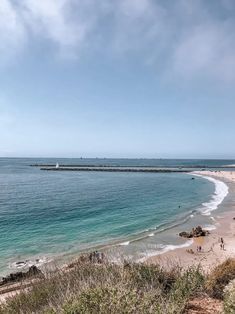 a beach with people walking on it next to the ocean