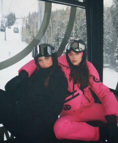 two women in ski gear sitting on a chair lift