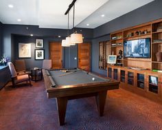 a pool table in the middle of a living room with built - in entertainment center