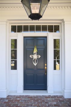 a blue front door with a lantern on the side and brick walkway leading up to it