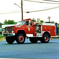 a red fire truck driving down a street next to power lines and telephone poles on a cloudy day