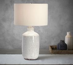 a table lamp sitting on top of a white counter next to a blue and white vase