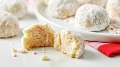 a white plate topped with snowball cookies next to a red napkin