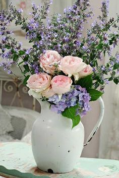 a white pitcher filled with pink and purple flowers