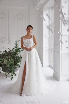 a woman in a white wedding dress standing next to a potted plant