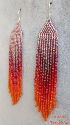 two pairs of beaded earrings with orange and red fringes on top of each other