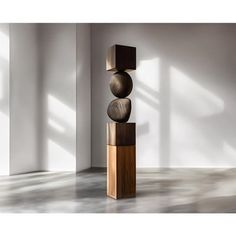 a tall wooden sculpture sitting on top of a floor next to a white wall and windows