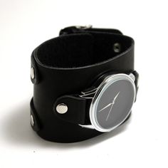 a black leather wrist watch sitting on top of a white table