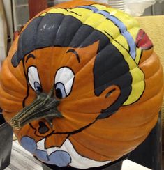 a pumpkin with a cartoon character painted on it's face sitting on a table