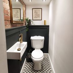 a white toilet sitting next to a sink in a bathroom under a mirror on the wall