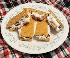 there are some cookies and marshmallows on the plate with plaid table cloth