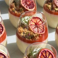 several glasses filled with dessert and garnished with orange slices, herbs and crumbs