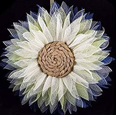 a white flower with blue and green feathers on it's center piece, hanging from a black background