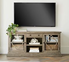 a flat screen tv mounted to the side of a wooden entertainment center with wicker baskets