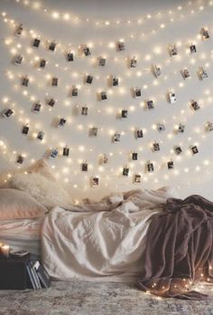 a bedroom with lights strung from the ceiling and pictures hanging on the wall above it