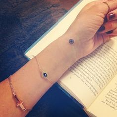 a woman's hand holding an open book with a blue evil eye on it