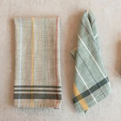 three folded towels and two napkins on a white tablecloth with one folded to the side