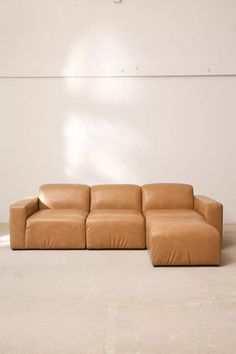 a brown leather couch sitting on top of a white floor