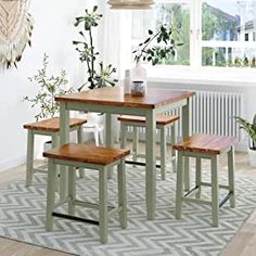 a kitchen table with four stools and a potted plant in the corner next to it