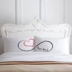 a white bed topped with two pillows next to a headboard