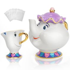 the beauty and the beast teapot is next to a cup with a napkin on it