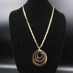 "DESCRIPTION: This designer necklace by Monet, dating back to the 1950s, embodies the era's classic style and sophistication. The piece showcases a striking gold tone medallion pendant that exudes an air of vintage elegance, skillfully matched with a complementary gold tone chain. The \"MONET\" mark certifies its authenticity and quality, reflecting the brand's longstanding reputation for timeless fashion. In excellent condition, this necklace has been impeccably preserved, allowing its wearer t Retro Yellow Gold Metal Jewelry, Formal Retro Pendant Jewelry, Retro Pendant Jewelry For Formal Occasions, Retro Formal Pendant Jewelry, Classic Gold Necklaces With Large Pendant, Vintage Brass Medallion Necklace, Classic Gold Necklace With Large Pendant, Retro Gold Metal Necklace, Retro Round Metal Necklaces