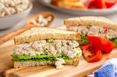 a cut in half sandwich sitting on top of a wooden cutting board