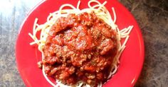 a red plate topped with spaghetti and sauce