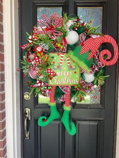 a christmas wreath on the front door with stockings and candy canes hanging from it