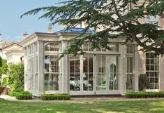 a large white house sitting on top of a lush green field next to a tree