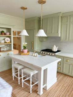 a model kitchen with green cabinets and white counter tops, two stools at the island