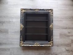 an ornate black and gold framed mirror on the wall