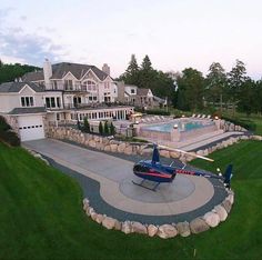 an aerial view of a house with a helicopter parked in the driveway and swimming pool