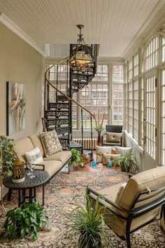 a living room filled with furniture next to a spiral stair case in front of a window