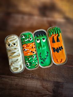 three tins filled with halloween treats sitting on top of a wooden table